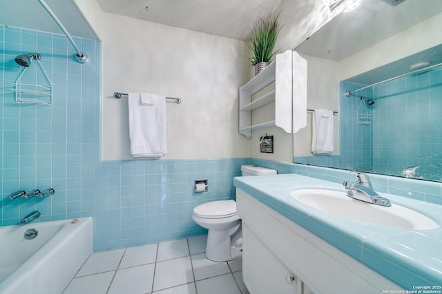 bathroom with vanity, tile walls, a textured ceiling, tile patterned floors, and shower / washtub combination