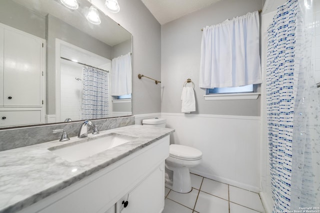 full bath with vanity, a shower with shower curtain, tile patterned flooring, toilet, and wainscoting