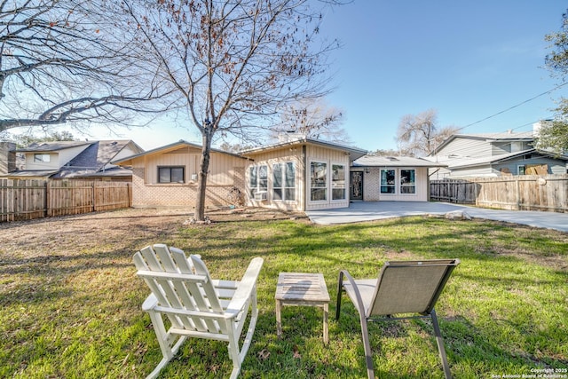 back of property with a lawn, a patio, fence private yard, and brick siding