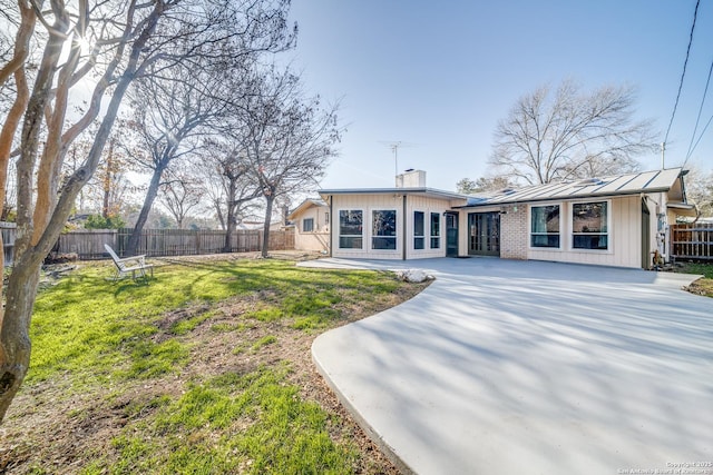 exterior space featuring a chimney, a front lawn, french doors, and fence