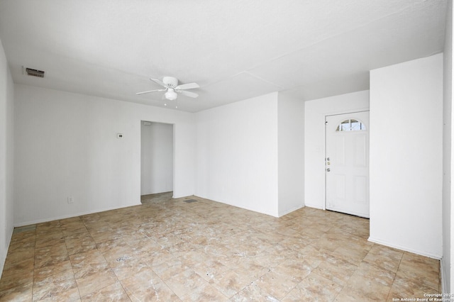 empty room with baseboards, ceiling fan, and visible vents