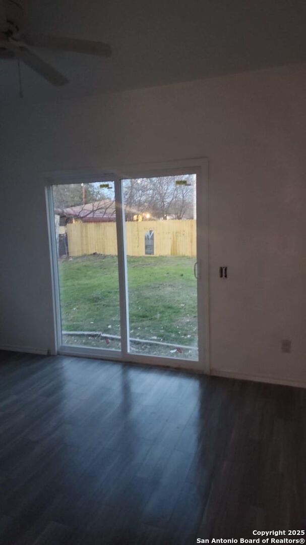 doorway to outside with baseboards, a ceiling fan, and dark wood-type flooring