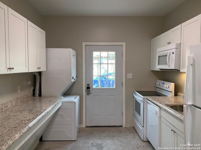 kitchen featuring stacked washer and dryer, white appliances, and white cabinets