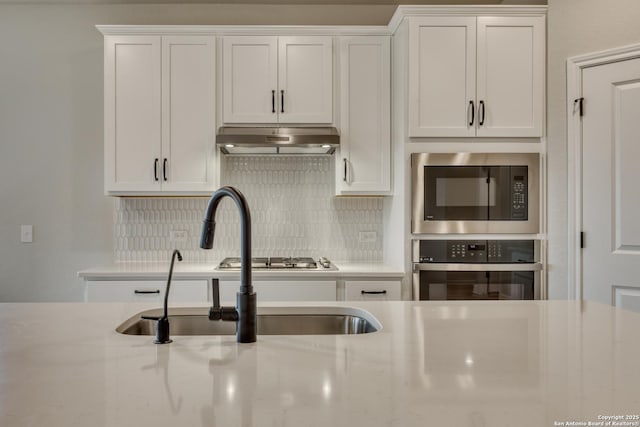 kitchen with white cabinets, appliances with stainless steel finishes, extractor fan, and backsplash