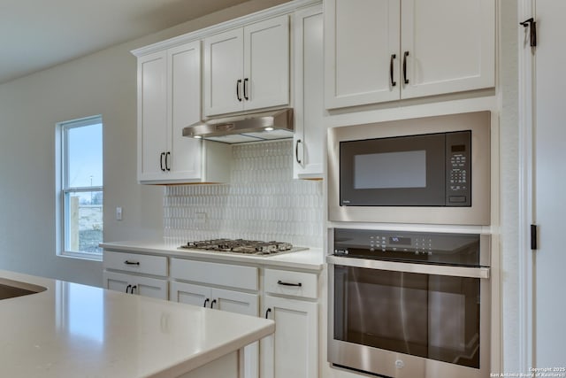 kitchen featuring stainless steel appliances, light countertops, white cabinetry, and under cabinet range hood