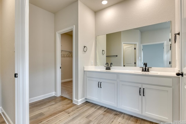 bathroom featuring double vanity, baseboards, a sink, and wood finished floors