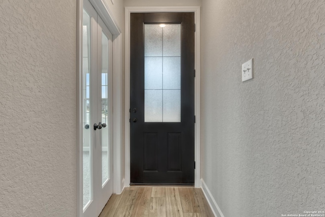 doorway to outside with a textured wall and light wood-style flooring