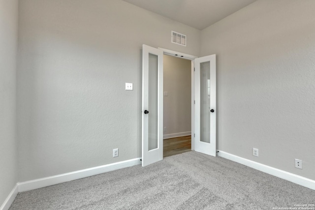 unfurnished room featuring light carpet, baseboards, visible vents, and french doors