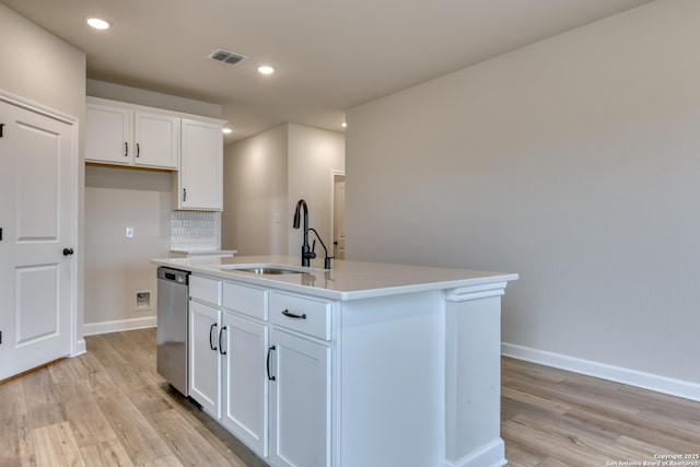 kitchen with a kitchen island with sink, white cabinetry, light countertops, and a sink