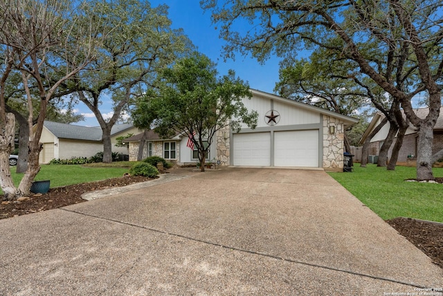 mid-century modern home with an attached garage, stone siding, a front yard, and driveway