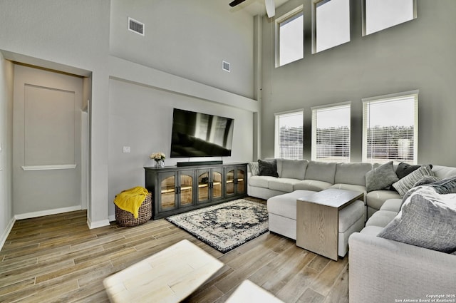 living room featuring a wealth of natural light, visible vents, baseboards, and wood finished floors