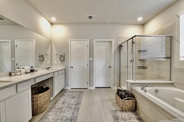 bathroom featuring a sink, visible vents, a bath, double vanity, and a stall shower