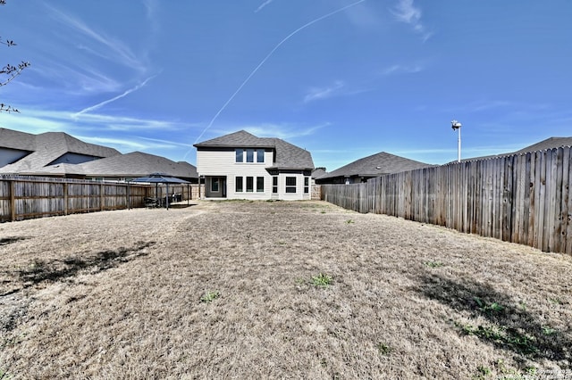 rear view of property featuring roof with shingles and a fenced backyard