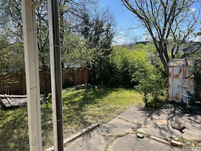 view of yard featuring a storage unit, an outdoor structure, and fence