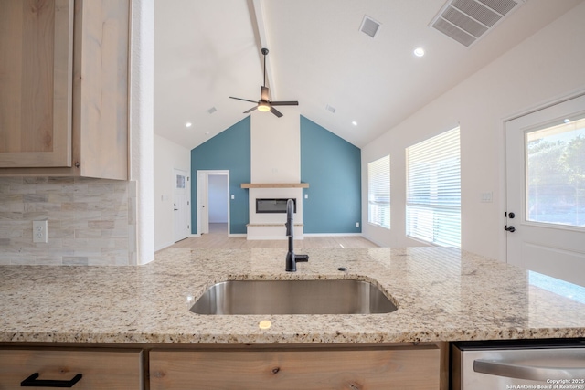 kitchen featuring light stone counters, visible vents, open floor plan, and a sink