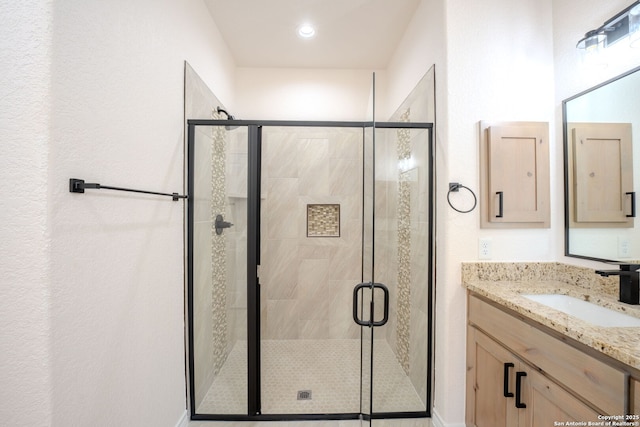 bathroom with a shower stall and vanity