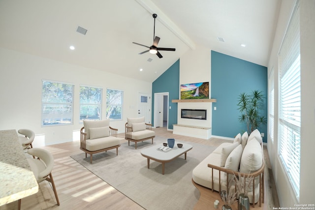 living room with high vaulted ceiling, visible vents, light wood-type flooring, beam ceiling, and a glass covered fireplace