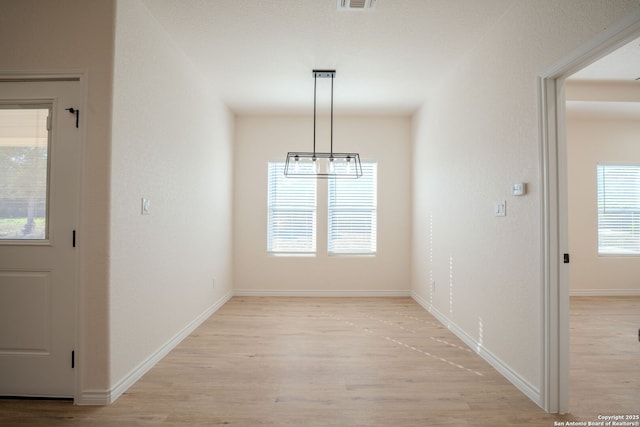 unfurnished dining area with baseboards, visible vents, and light wood finished floors