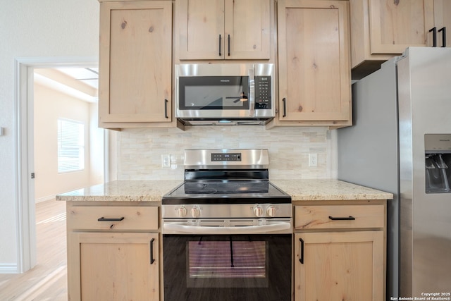 kitchen featuring light stone countertops, light brown cabinets, and appliances with stainless steel finishes