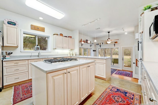 kitchen featuring light countertops, stainless steel gas stovetop, a peninsula, and a center island