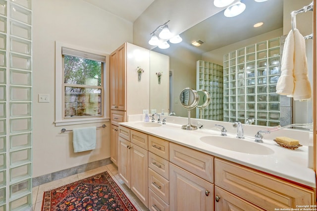 full bath featuring tile patterned flooring, a sink, baseboards, and double vanity