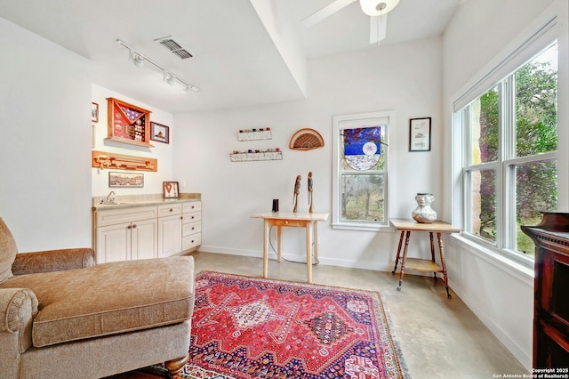 living area featuring concrete flooring, a wealth of natural light, visible vents, and baseboards