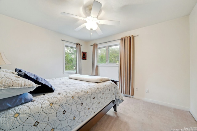 bedroom featuring light carpet, a ceiling fan, and baseboards