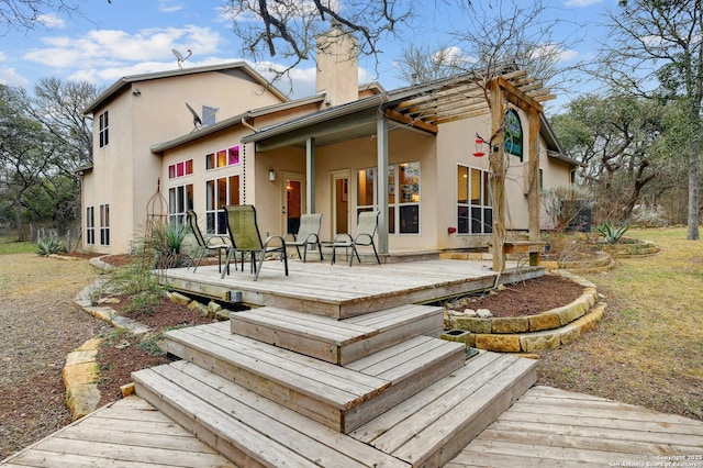 rear view of property with a chimney, a deck, and stucco siding