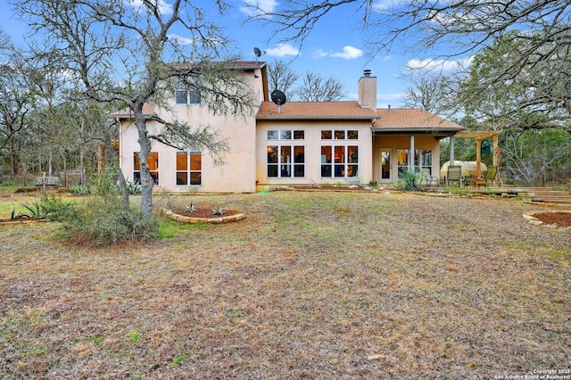 rear view of property with a chimney and stucco siding