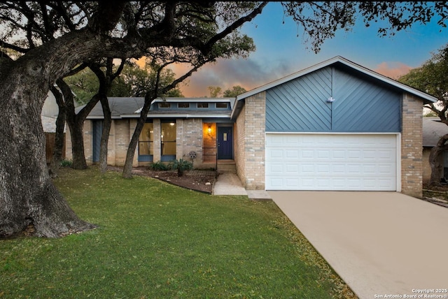 mid-century inspired home featuring a garage, concrete driveway, brick siding, and a front lawn