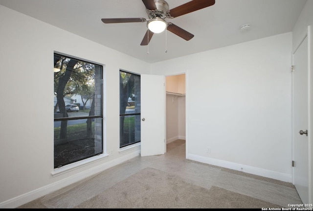 unfurnished bedroom with ceiling fan, a spacious closet, and baseboards