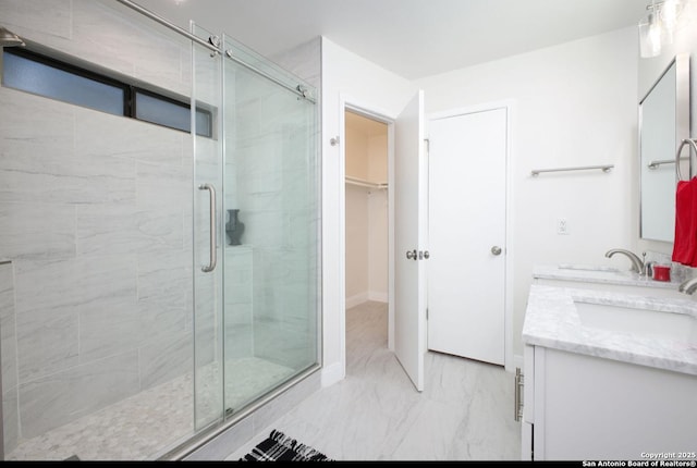 bathroom featuring marble finish floor, double vanity, a sink, and a shower stall