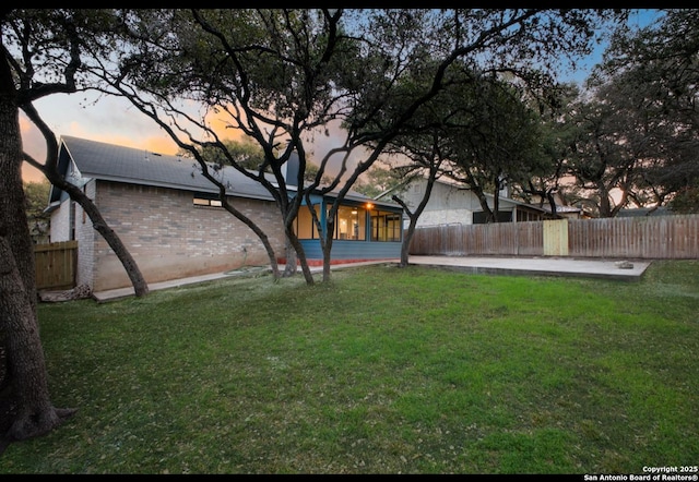 view of yard featuring a sunroom, fence, and a patio