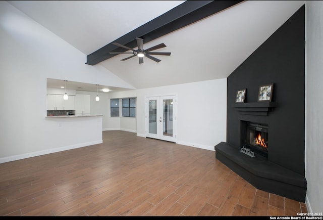 unfurnished living room with a large fireplace, french doors, wood finished floors, and beam ceiling