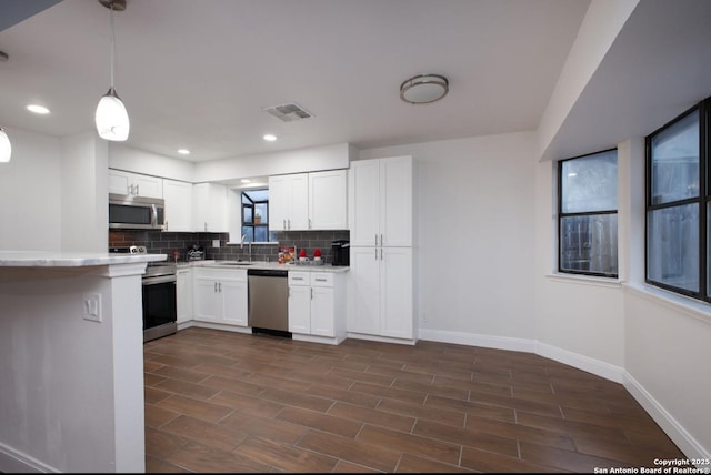 kitchen with stainless steel appliances, light countertops, white cabinets, and pendant lighting