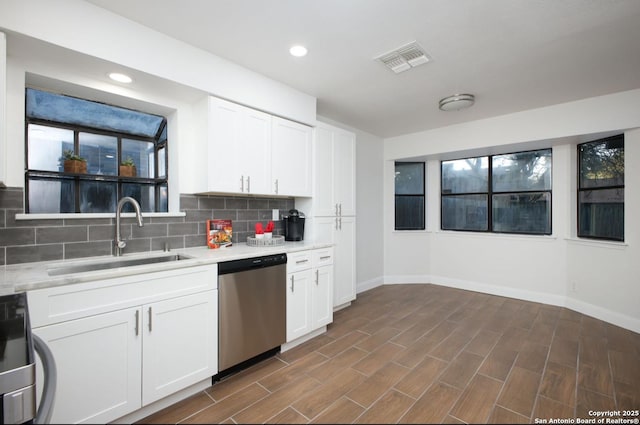 kitchen featuring light countertops, dishwasher, a sink, and white cabinetry