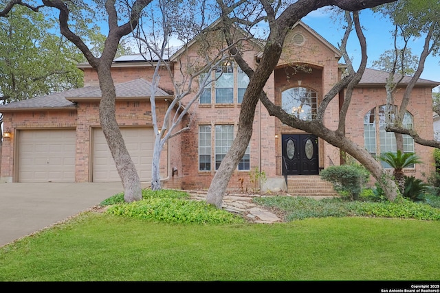 view of front of home featuring a garage, driveway, brick siding, and a front yard