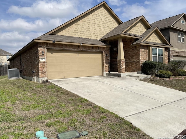 craftsman inspired home with brick siding, concrete driveway, central AC, a garage, and a front lawn