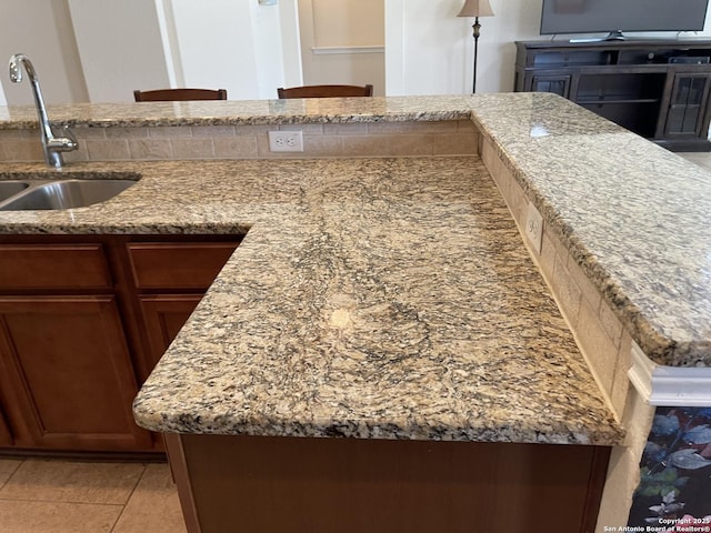 kitchen featuring light stone counters, a sink, and light tile patterned flooring