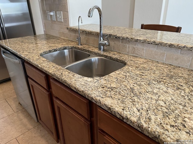 kitchen with light tile patterned floors, tasteful backsplash, a sink, and light stone countertops