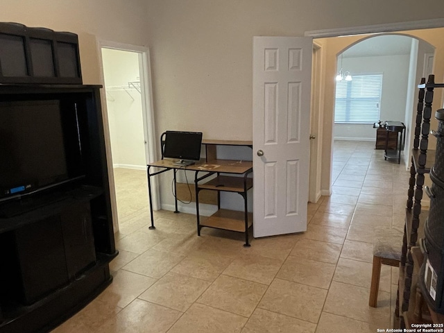 office space with arched walkways, light tile patterned floors, and baseboards