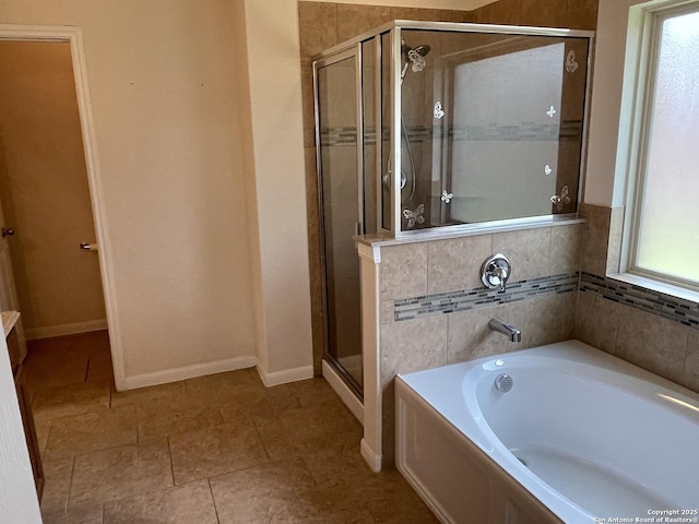 full bath featuring tile patterned flooring, a shower stall, baseboards, and a bath