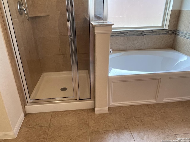 bathroom with a garden tub, a shower stall, baseboards, and tile patterned flooring