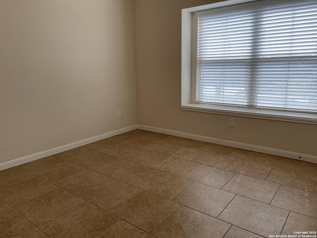 spare room with light tile patterned floors and baseboards