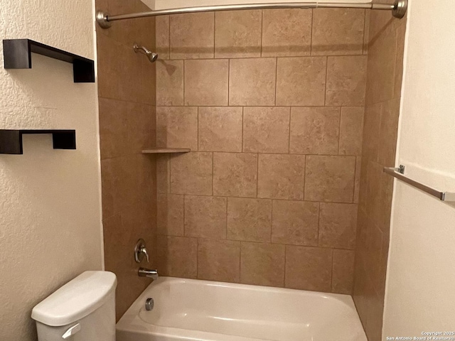 bathroom featuring toilet, a textured wall, and shower / bathtub combination