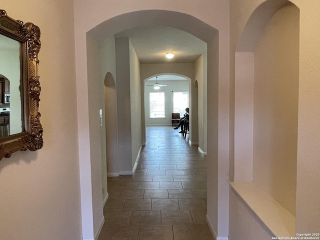 corridor with dark tile patterned flooring and baseboards