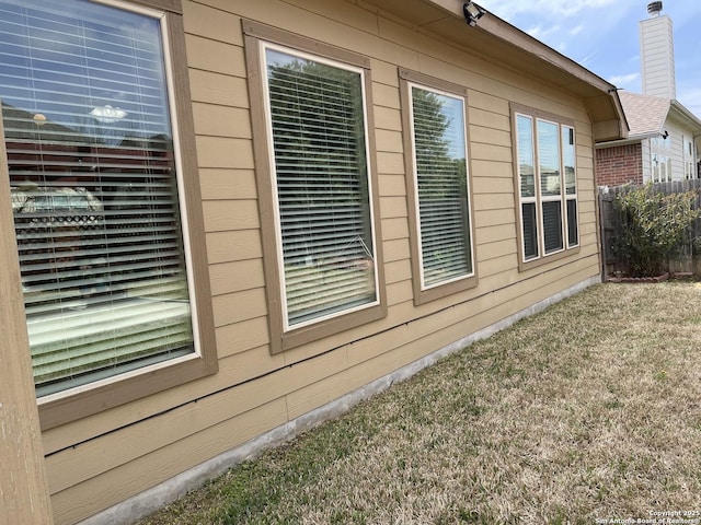 view of side of property with a chimney, fence, and a yard