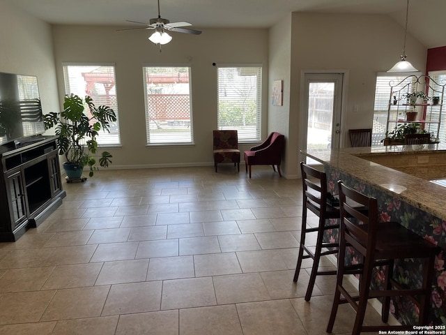 dining room with a ceiling fan, vaulted ceiling, baseboards, and light tile patterned floors