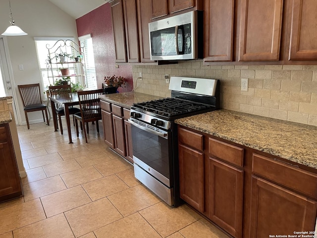 kitchen with light tile patterned floors, tasteful backsplash, decorative light fixtures, vaulted ceiling, and stainless steel appliances