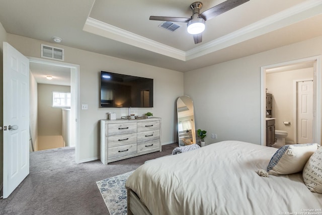 bedroom with baseboards, visible vents, a raised ceiling, ornamental molding, and dark carpet